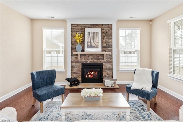 living area featuring a stone fireplace, wood finished floors, and baseboards