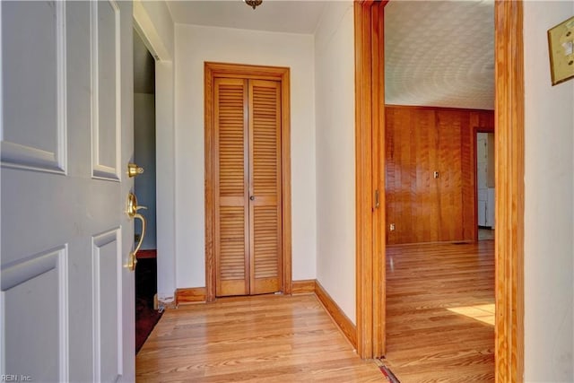 hallway featuring light hardwood / wood-style flooring and wooden walls