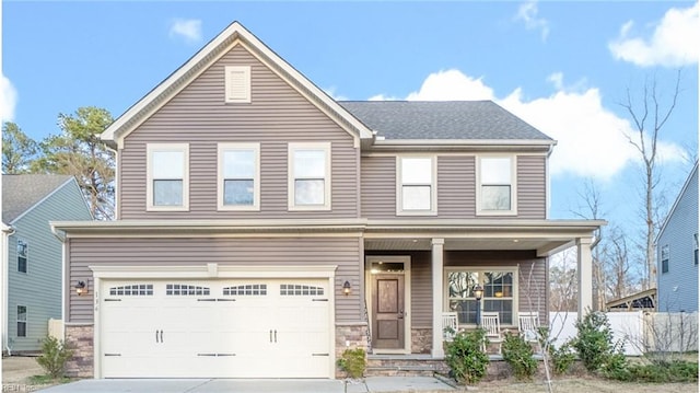 traditional home with driveway, covered porch, an attached garage, and stone siding