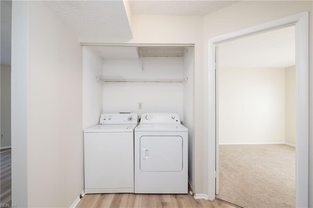 washroom featuring washing machine and dryer, a textured ceiling, and light hardwood / wood-style flooring