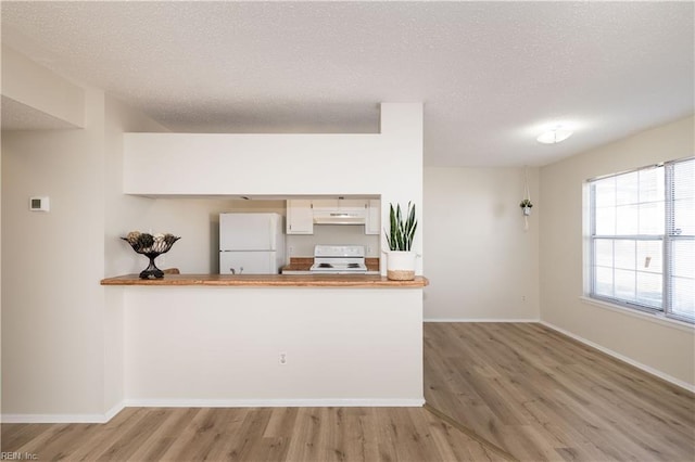 kitchen with kitchen peninsula, light hardwood / wood-style flooring, white appliances, a textured ceiling, and white cabinets