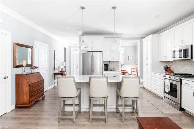 kitchen featuring high end appliances, an island with sink, light countertops, white cabinetry, and pendant lighting