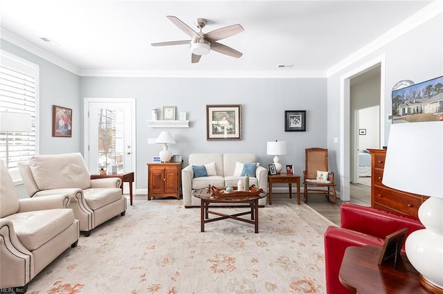 living room featuring ceiling fan, visible vents, and crown molding