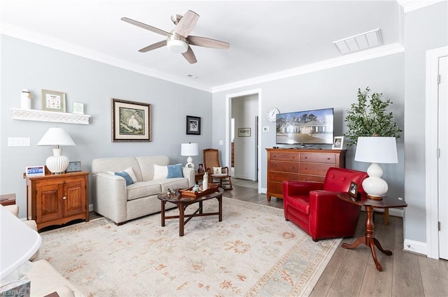 living area with light wood-style flooring, visible vents, ceiling fan, and crown molding