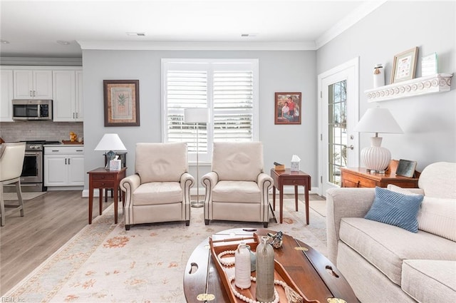 living area featuring a healthy amount of sunlight, light wood-style flooring, visible vents, and crown molding