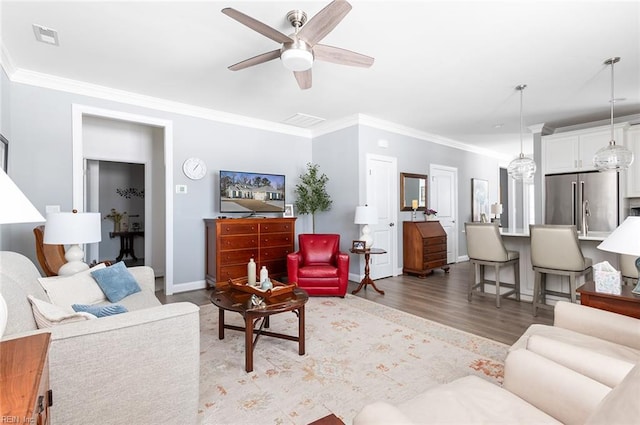 living room with ceiling fan, light wood finished floors, visible vents, and crown molding