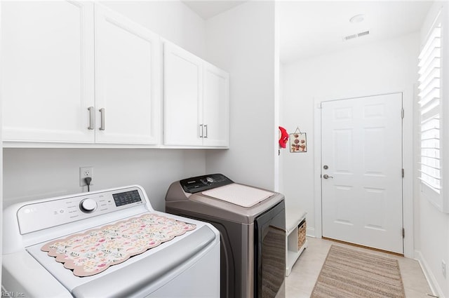 clothes washing area featuring baseboards, cabinet space, visible vents, and washing machine and clothes dryer