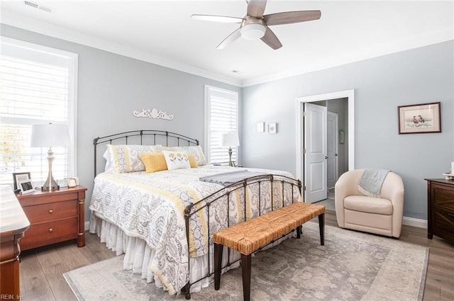 bedroom featuring crown molding, visible vents, ceiling fan, wood finished floors, and baseboards