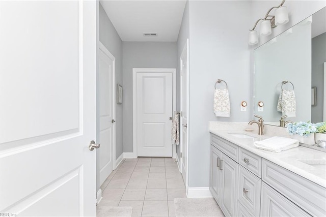 bathroom featuring double vanity, visible vents, a sink, baseboards, and tile patterned floors