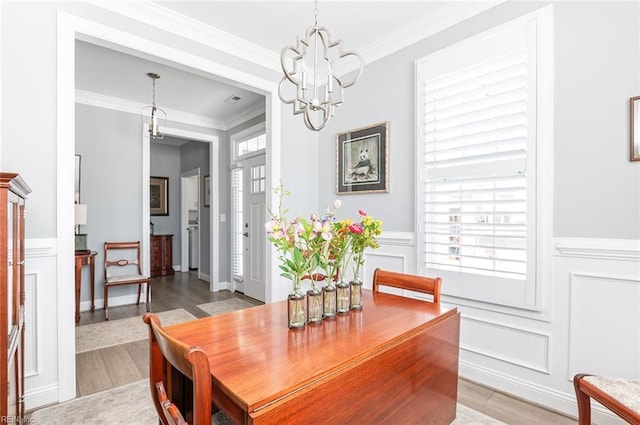 dining room featuring a chandelier, a healthy amount of sunlight, and a decorative wall