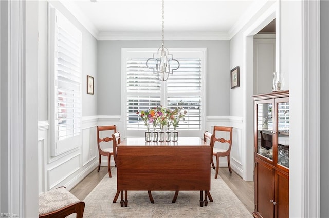 dining room featuring a healthy amount of sunlight, crown molding, and wainscoting