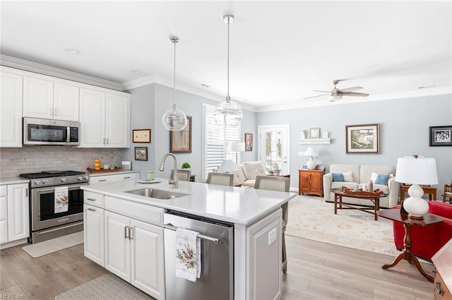 kitchen with appliances with stainless steel finishes, white cabinets, light countertops, and a sink