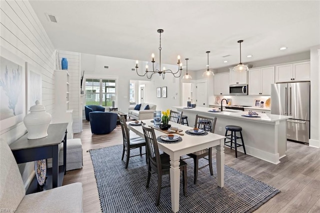 dining space with a notable chandelier, light hardwood / wood-style flooring, and sink