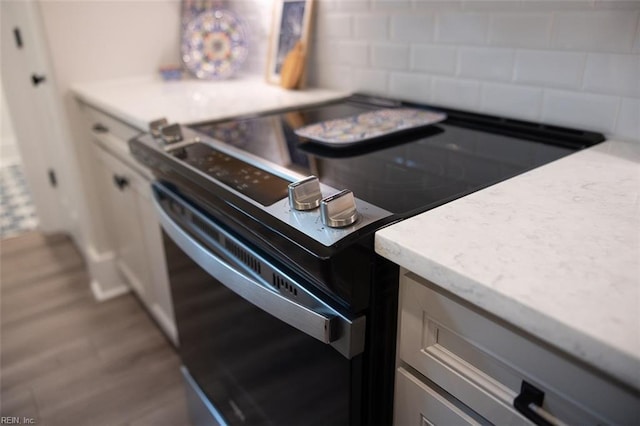 kitchen with hardwood / wood-style flooring, decorative backsplash, and electric range