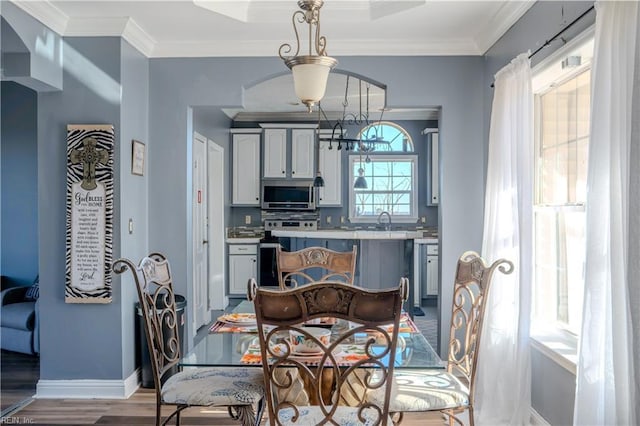 dining room featuring an inviting chandelier, crown molding, baseboards, and wood finished floors