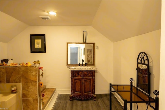 bathroom with visible vents, vaulted ceiling, vanity, wood finished floors, and baseboards