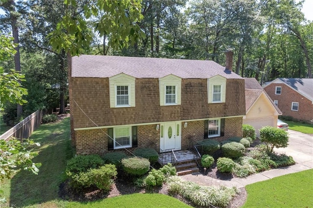 view of front of house featuring driveway, roof with shingles, fence, and brick siding