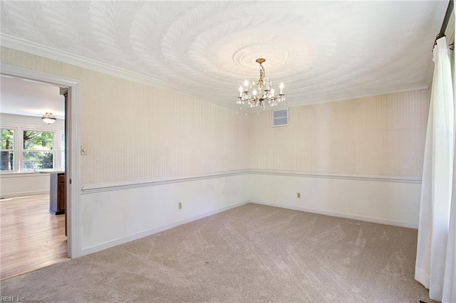 spare room with carpet floors, visible vents, crown molding, and an inviting chandelier