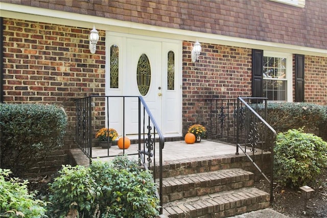 property entrance with a shingled roof and brick siding