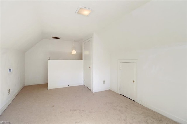 additional living space with lofted ceiling, visible vents, and light colored carpet