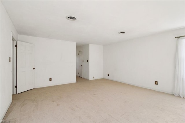 spare room featuring visible vents and light colored carpet