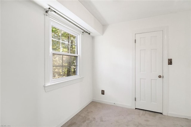 unfurnished room featuring light carpet and baseboards