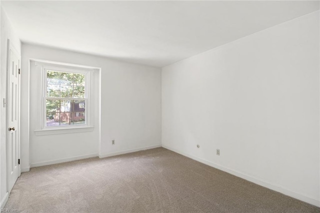 empty room featuring light carpet and baseboards