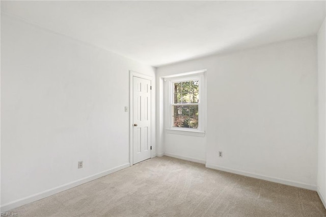 spare room with baseboards and light colored carpet