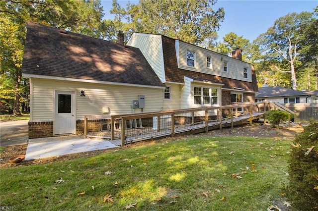 rear view of house with a chimney, a lawn, a patio area, and a wooden deck