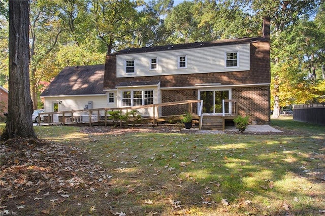 rear view of property featuring a yard, a chimney, a deck, and brick siding