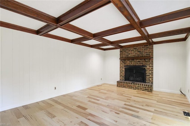 unfurnished living room featuring light wood finished floors, a brick fireplace, coffered ceiling, and beamed ceiling