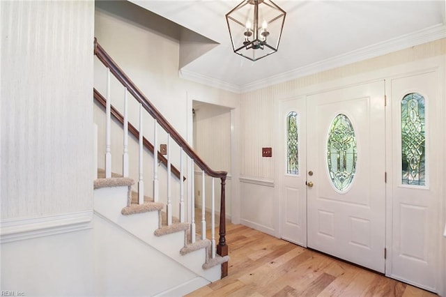 foyer entrance with light wood-type flooring, a notable chandelier, stairway, and crown molding