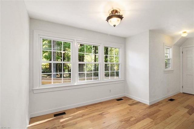 unfurnished room featuring light wood-style flooring, visible vents, and baseboards