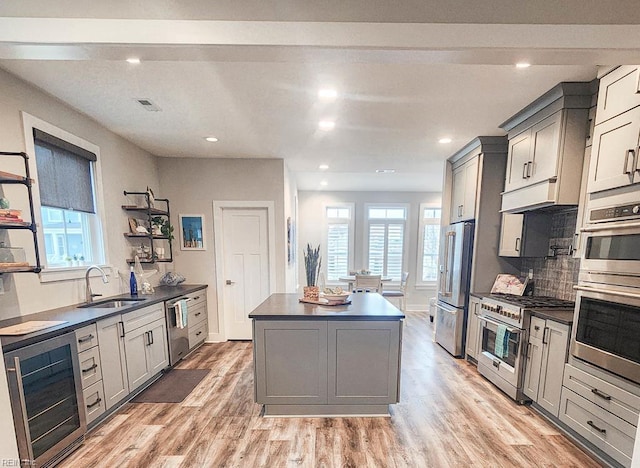 kitchen featuring high end appliances, gray cabinets, sink, and a center island