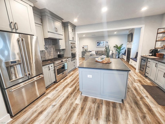 kitchen featuring gray cabinetry, a kitchen island, light hardwood / wood-style floors, high end appliances, and beverage cooler