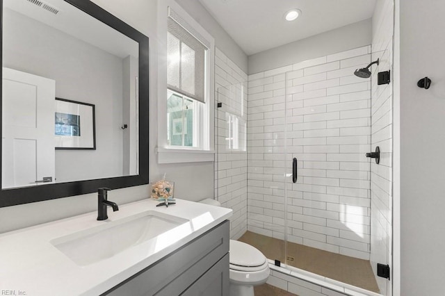 bathroom featuring toilet, vanity, and a shower with door