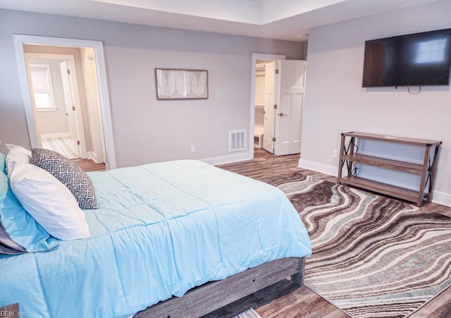 bedroom with hardwood / wood-style flooring and connected bathroom