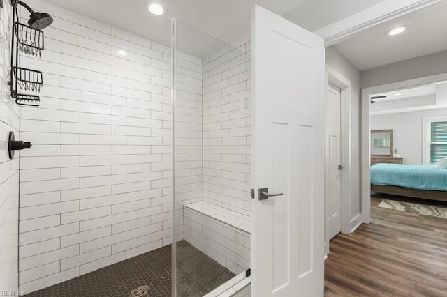 bathroom with a tile shower and wood-type flooring