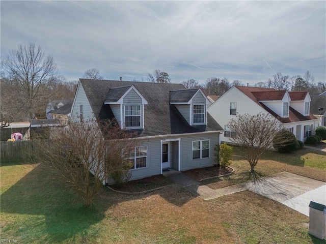 cape cod-style house featuring a shingled roof, a patio, and a front lawn