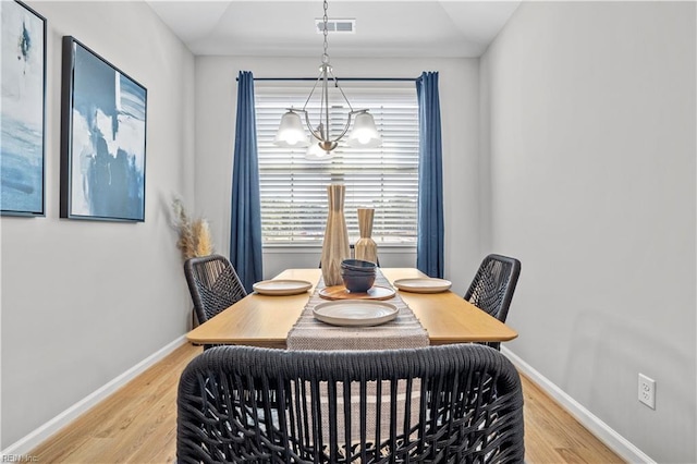 dining space featuring baseboards, wood finished floors, visible vents, and an inviting chandelier