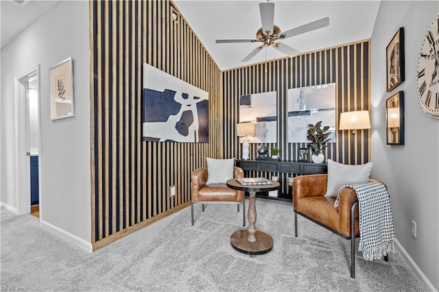 sitting room with an accent wall, a ceiling fan, baseboards, vaulted ceiling, and carpet