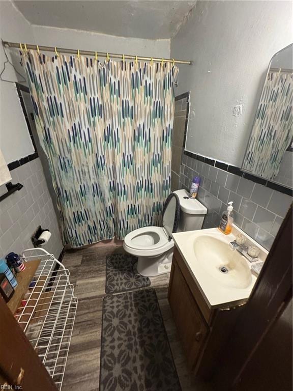 bathroom featuring a shower with curtain, tile walls, vanity, toilet, and hardwood / wood-style flooring