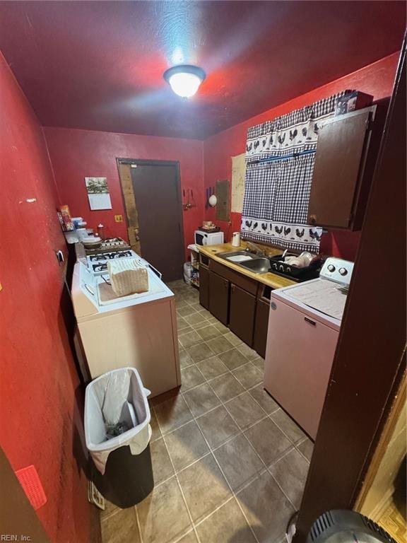 kitchen with dark brown cabinetry, washer / dryer, tile patterned flooring, and sink