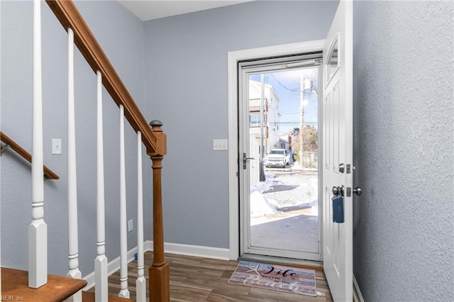 entryway with stairway, baseboards, wood finished floors, and a textured wall