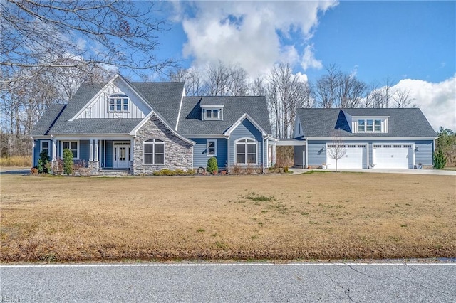 craftsman-style home with a front yard, a garage, stone siding, and board and batten siding