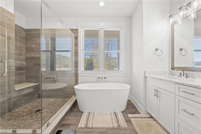 bathroom with a soaking tub, a stall shower, baseboards, vanity, and wood finished floors