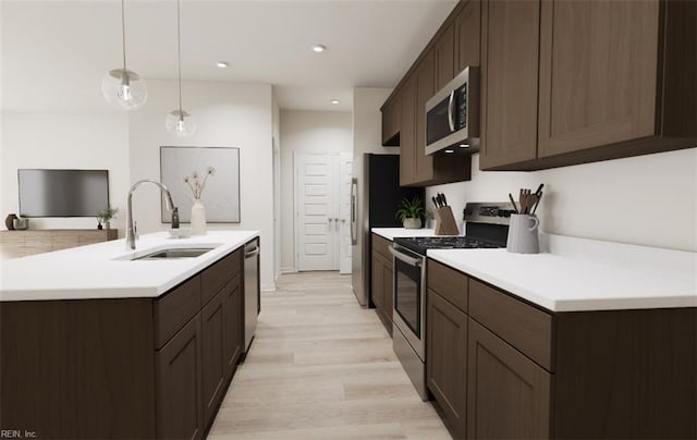 kitchen featuring hanging light fixtures, stainless steel appliances, dark brown cabinetry, light hardwood / wood-style floors, and sink