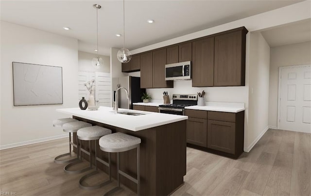 kitchen featuring appliances with stainless steel finishes, a center island with sink, dark brown cabinets, decorative light fixtures, and sink