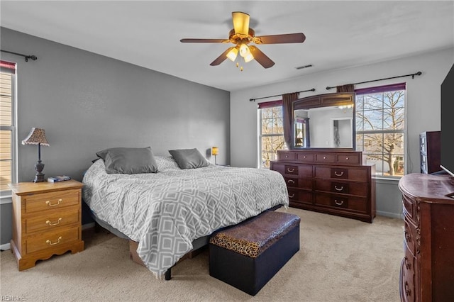 bedroom with multiple windows, ceiling fan, and light colored carpet