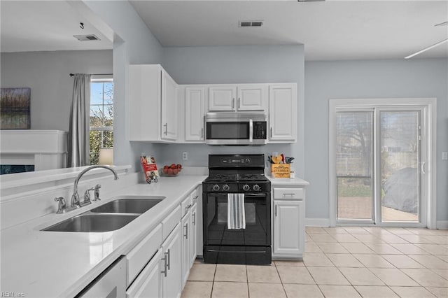 kitchen with light tile patterned floors, sink, gas stove, and white cabinets